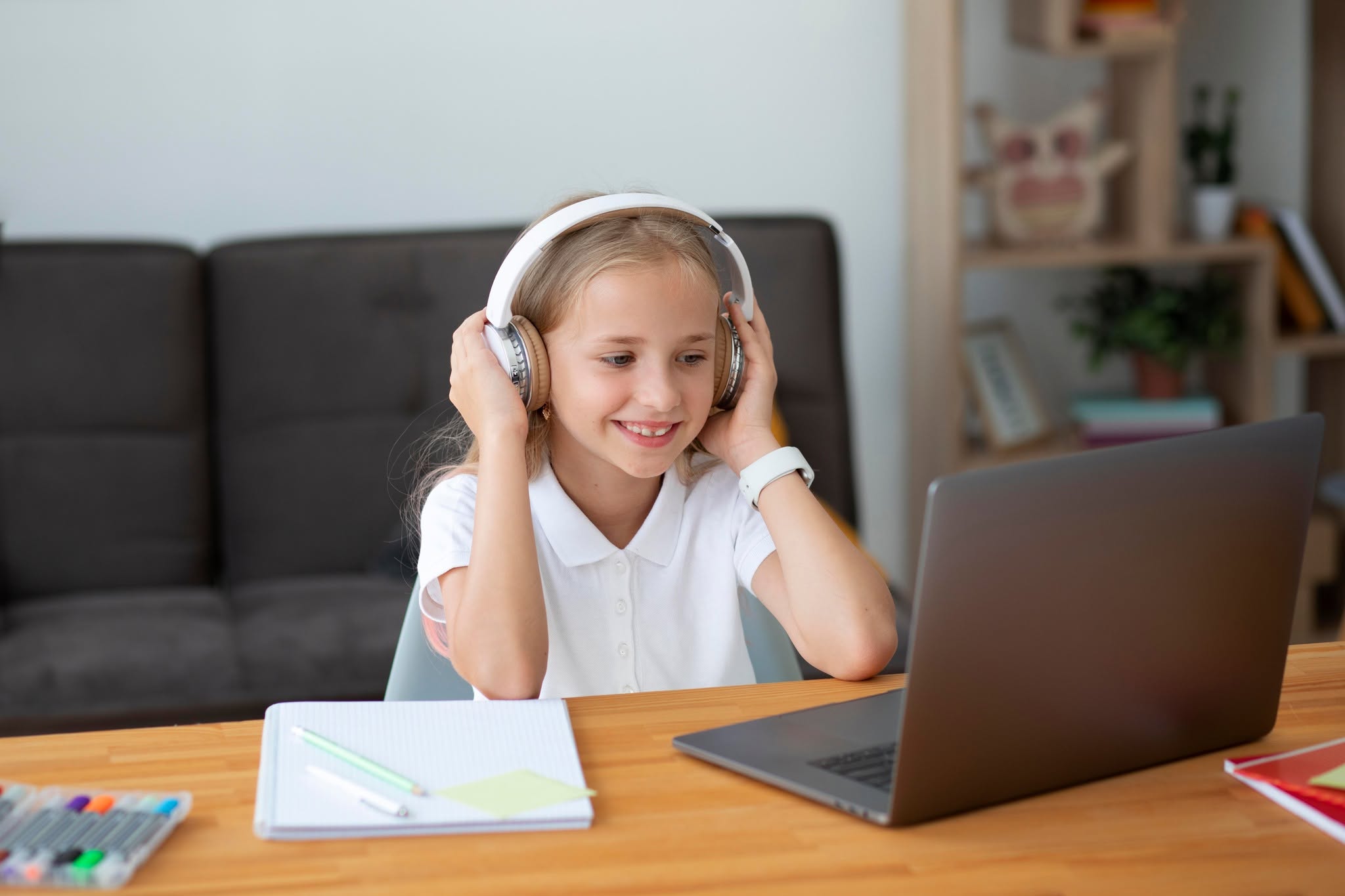 Young girl with headphones smiling during online elementary school class